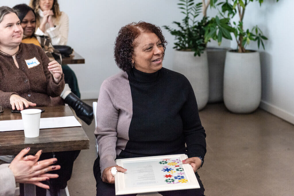 A seated woman holds a framed picture.