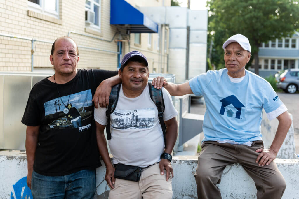 Three men outside a homeless shelter