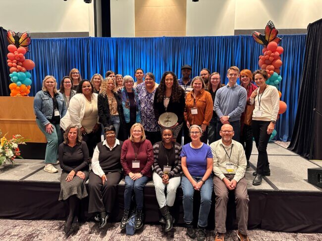 A group of people pose for a photo on a stage