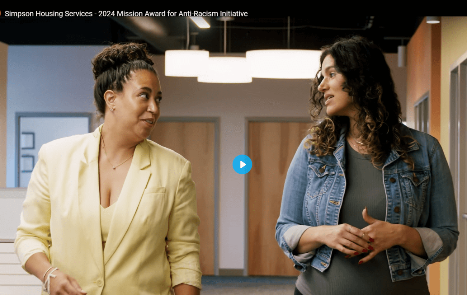 Two women converse as they walk in an office